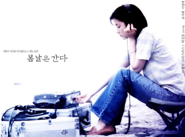 이영애가 청바지에 흰티를 입고 음향장비인듯 보이는 기계에 연결된 헤드폰을 쓰고 앉아있다.